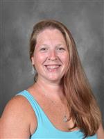 Janet Newby is wearing a blue shirt. She has long hair. 
