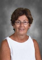 Regina Pollock  has short hair and glasses, she is wearing a white shirt